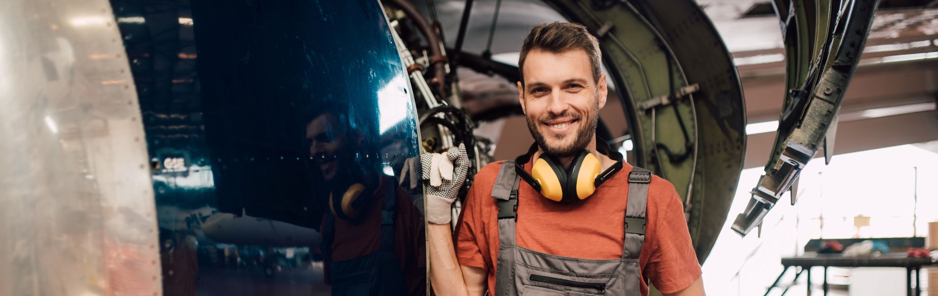 Homme souriant devant un avion en construction
